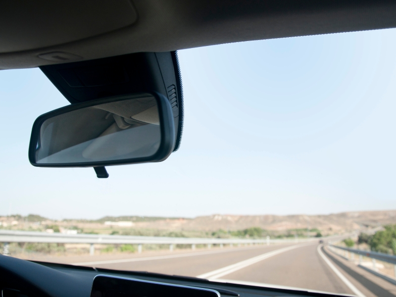 Replacing a Nissan windscreen? View from inside car, driving on open highway with clear sky.