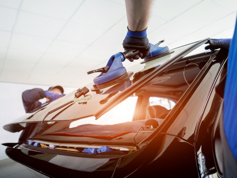 Technicians lifting rear glass showing labour in the cost to replace car windscreen