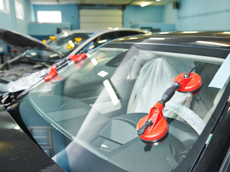 Suction tools attached to glass showing setup phase in cost to replace car windscreen
